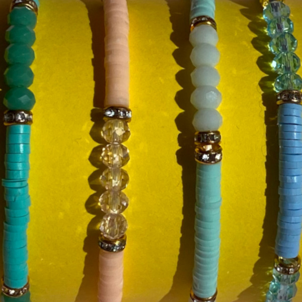 Amy armbånd med perler og similisten i fire farver set tæt på gul baggrund