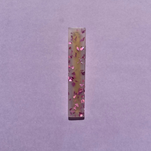 Bella hårklemme med pink glitter præget i overfladen på lilla baggrund