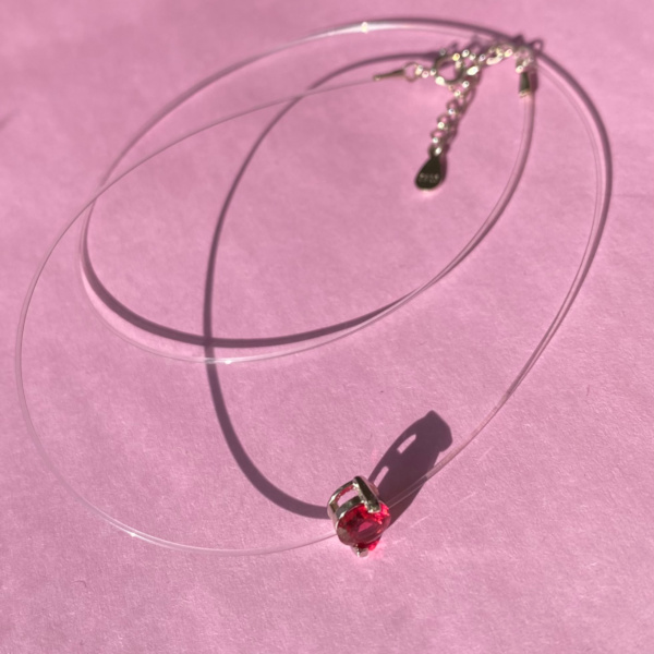Marbel halskaede med roed zirkon i soelvindfatning på 'usynlig' kaede paa rosa baggrund