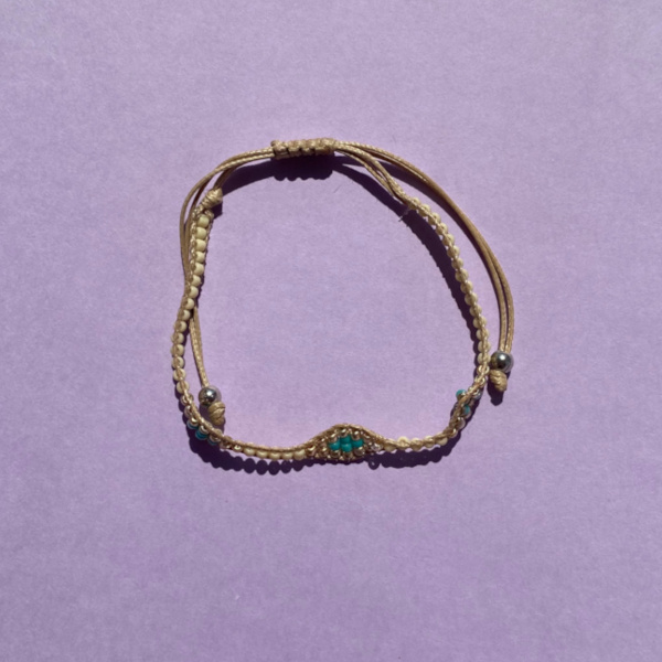 Marge armbånd med beige og turkise perler på lilla baggrund
